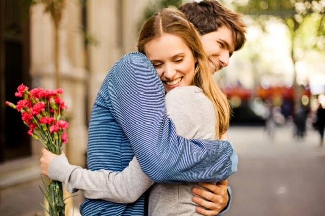 guy hugs woman with flowers